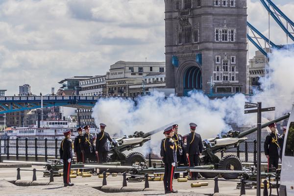 Soldiers fire a Royal Salute in front of Tower Bridge, London