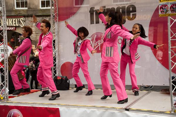 Energetic tap dancers dressed in pink suits on the Royal Mile