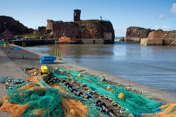 Dunbar Castle seen from harbour with fishing nets in foreground
