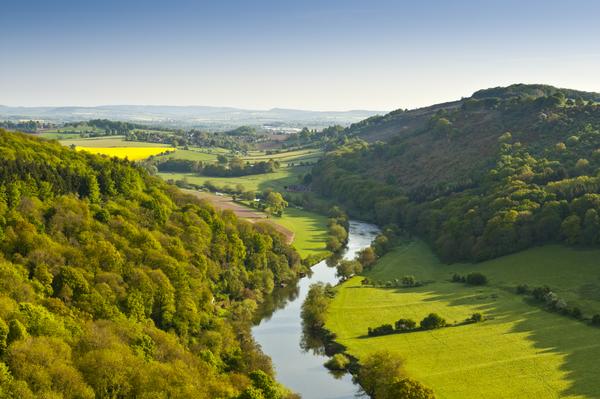 Meandering River Wye making its way through lush green rural farmland in the warm early sunlight