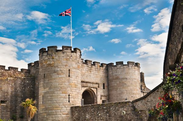 Union flag flies against a blue sky over the main entrance and guard towers to Stirling Castle