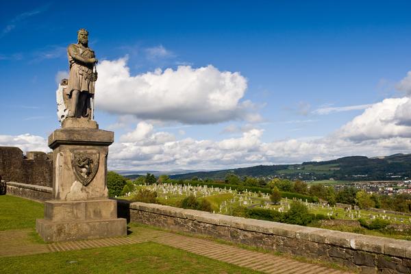 Statue of King Robert The Bruce statue against a blue sky and view to distant hills, in Stirling Castle