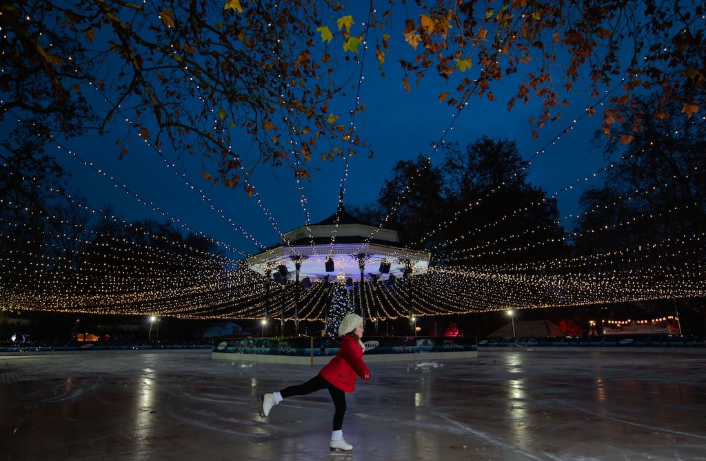 Girl skating at night on ice rink in Hyde Park, illuminated with fairy lights