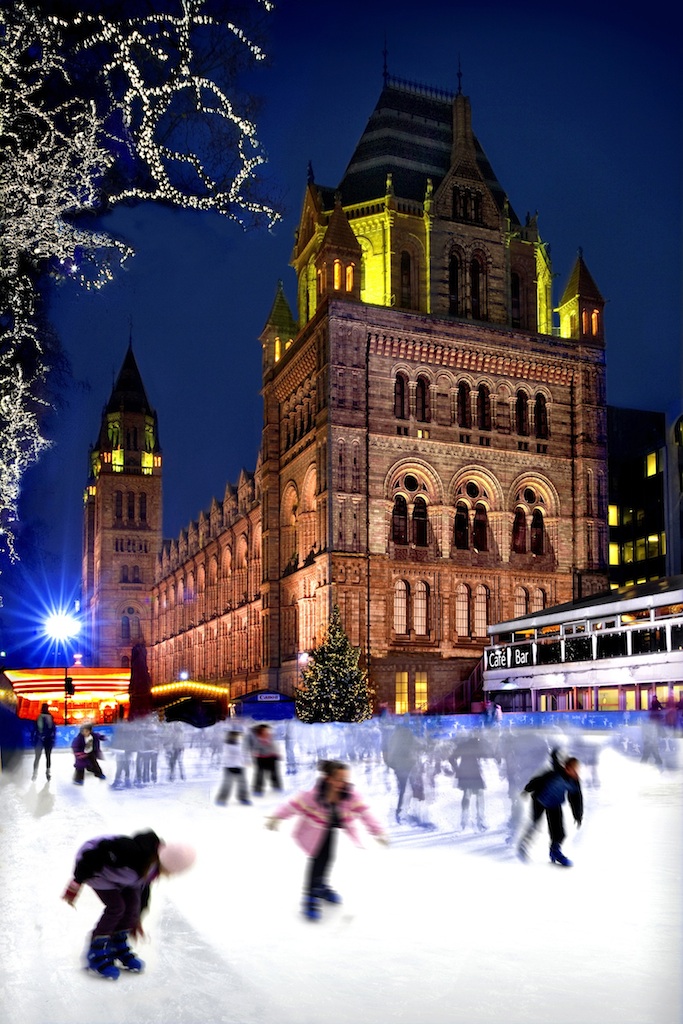 Ice rink in foreground at night, with the Natural History Museum lit up in the background