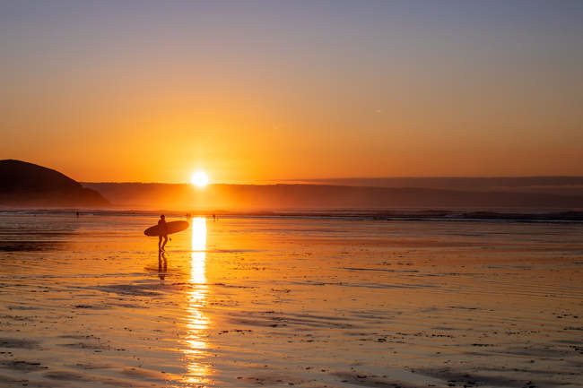 A surfer at sunset on Westward Ho! Beach
